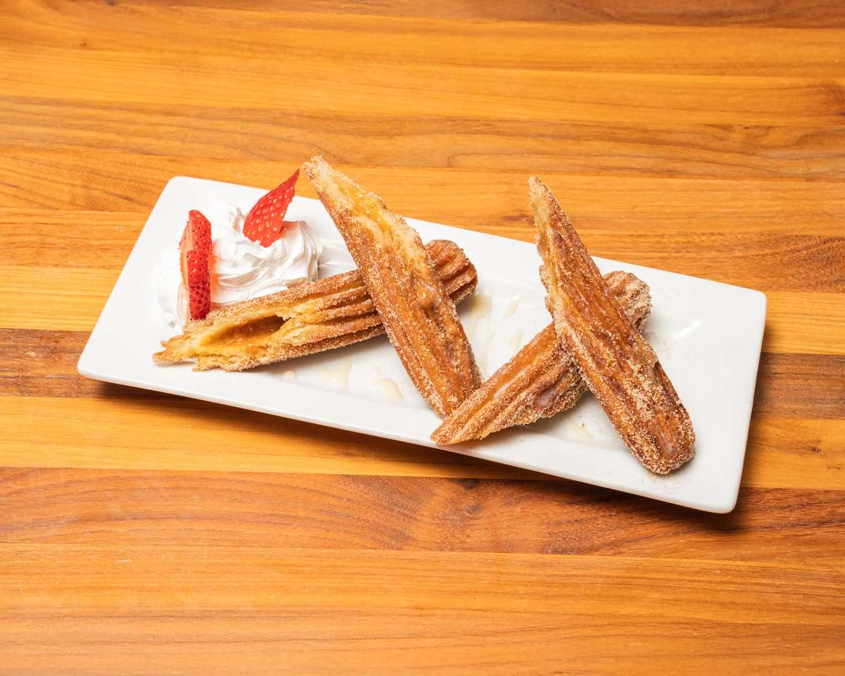Churros dusted with cinnamon sugar served with whipped cream and fresh strawberries.
