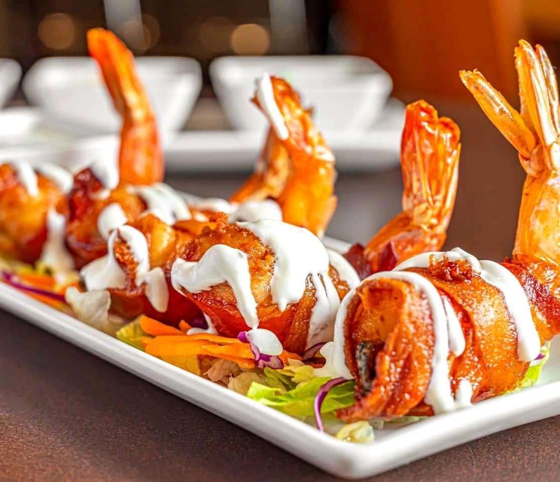 Mesero bacon-wrapped shrimp served with crema.