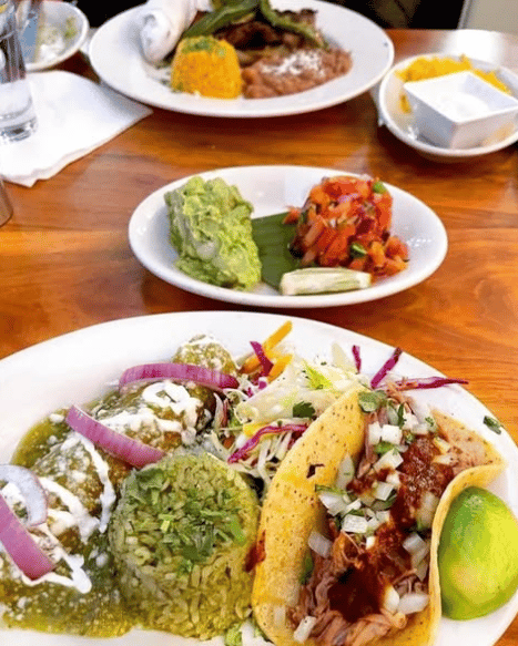 A colorful plate of enchiladas, rice, tacos, and slaw served at Mesero with guac and salsa.