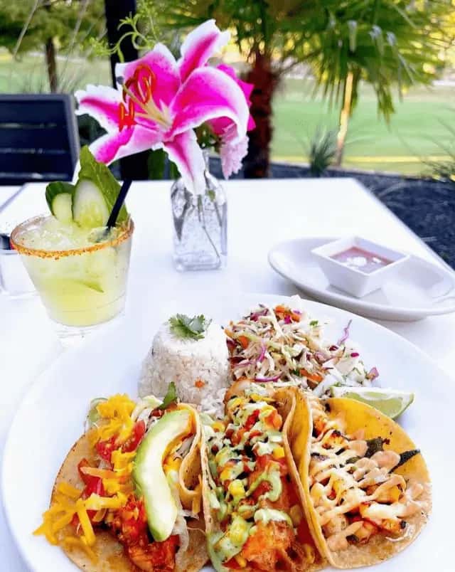 Colorful taco plate with rice, slaw, and a cucumber margarita served on Mesero's lush outdoor patio.