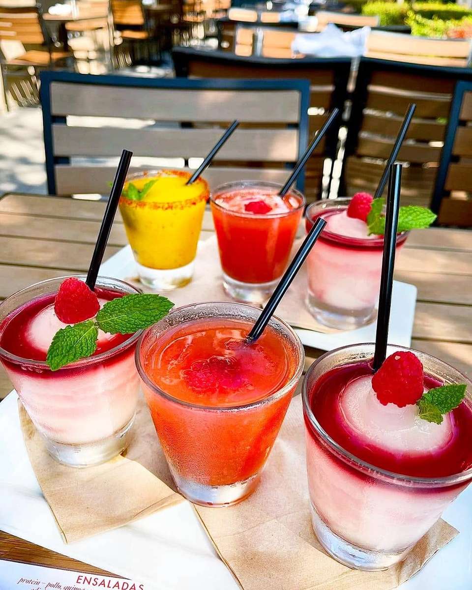 Colorful Mesero margaritas and cocktails served together on an outdoor dining table.