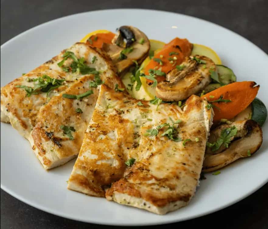 Grilled chicken paillard with veggies, garnished with herbs, served at Mesero.