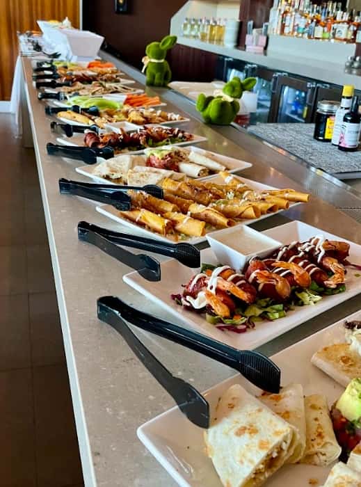 Mesero catering spread with tacos, wraps, shrimp bites, and fresh appetizers on bar counter.