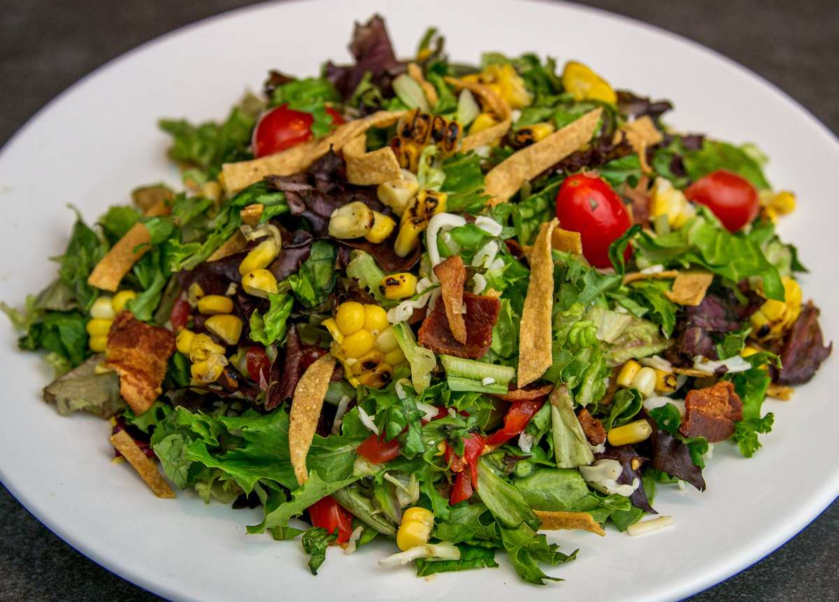 Mesero salad with greens, roasted corn, tomatoes, tortilla strips, and fresh herbs.