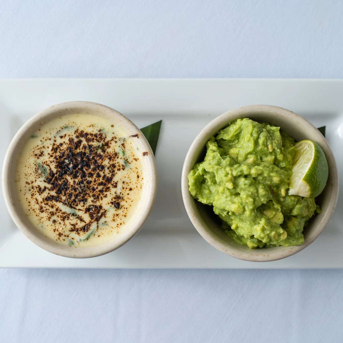 Mesero queso and fresh guacamole served side by side for sharing at the table.