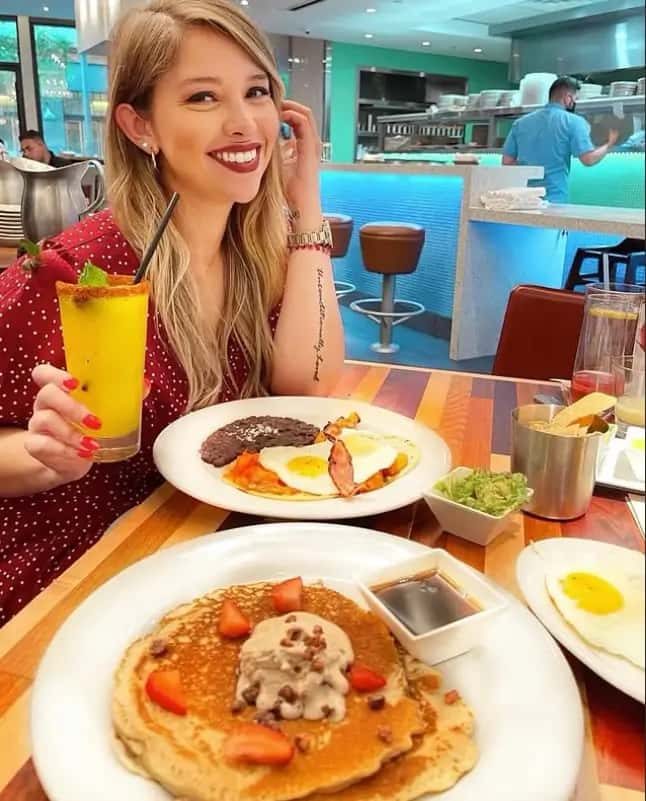 Mesero brunch scene with a guest enjoying pancakes, eggs, bacon, and a tropical drink inside the restaurant.