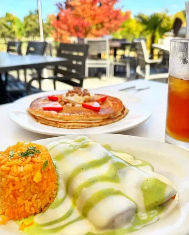 A colorful plate of enchiladas with rice, pancakes, and iced tea at Mesero.