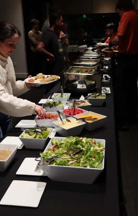 Guests serving themselves at the Mesero buffet with fresh salads and toppings on a modern dinner table.