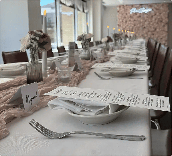 Upscale dining table setting with personalized place card 'Miguel', white dishware, and printed menu at formal restaurant.