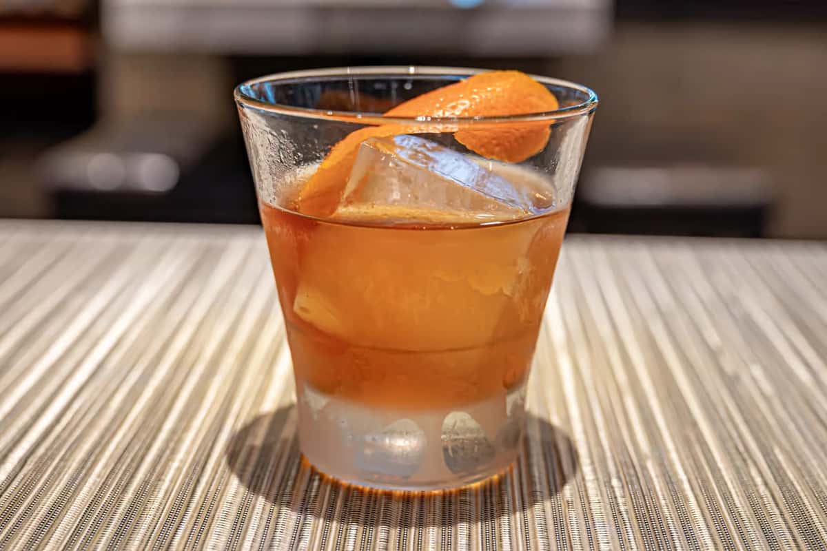 Mesero Old Fashioned cocktail served with a citrus twist in a clear glass on a textured table.