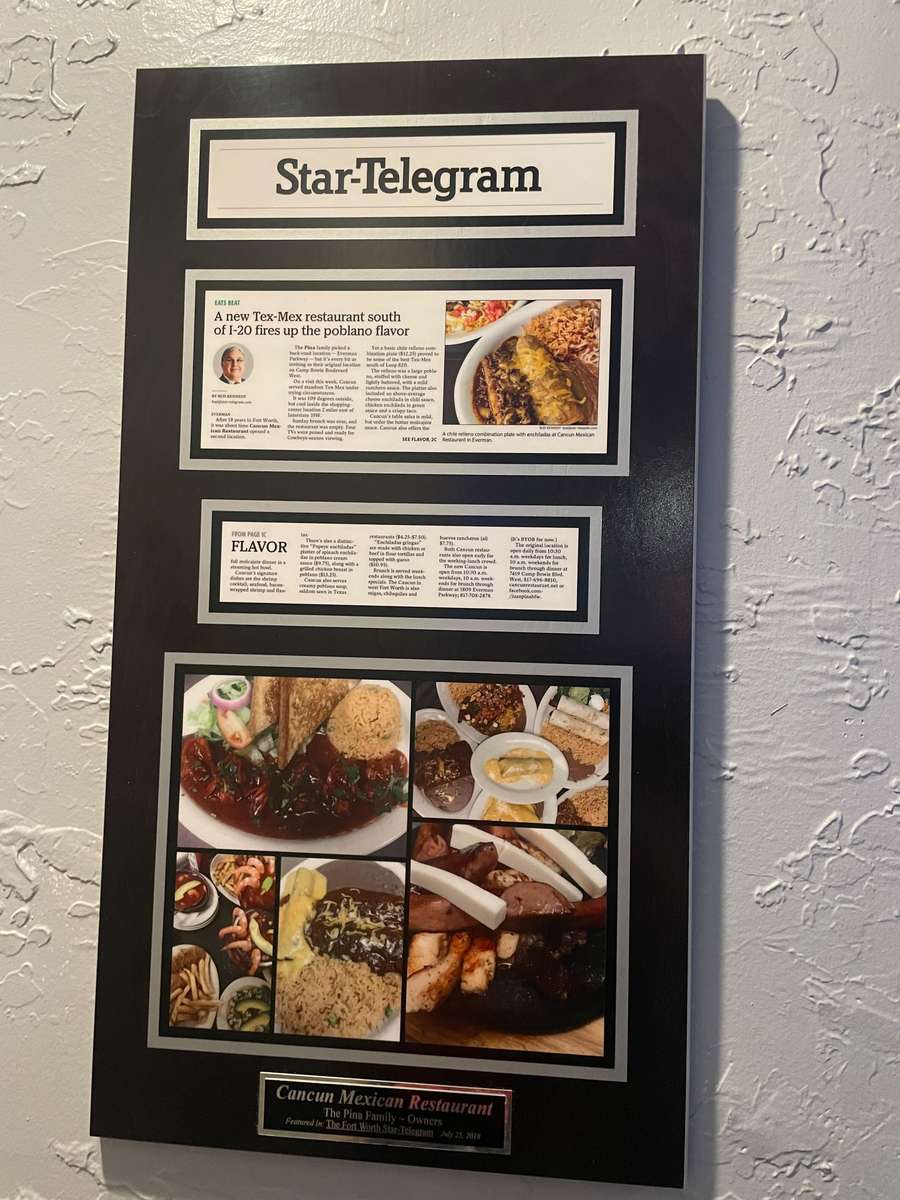 Framed wall placard displaying a Fort Worth Star-Telegram press article about Cancun Mexican Restaurant, featuring the Piña family. Includes article headlines, a photo of a dish with rice and poblano sauce, and a collage of various plated Mexican dishes.