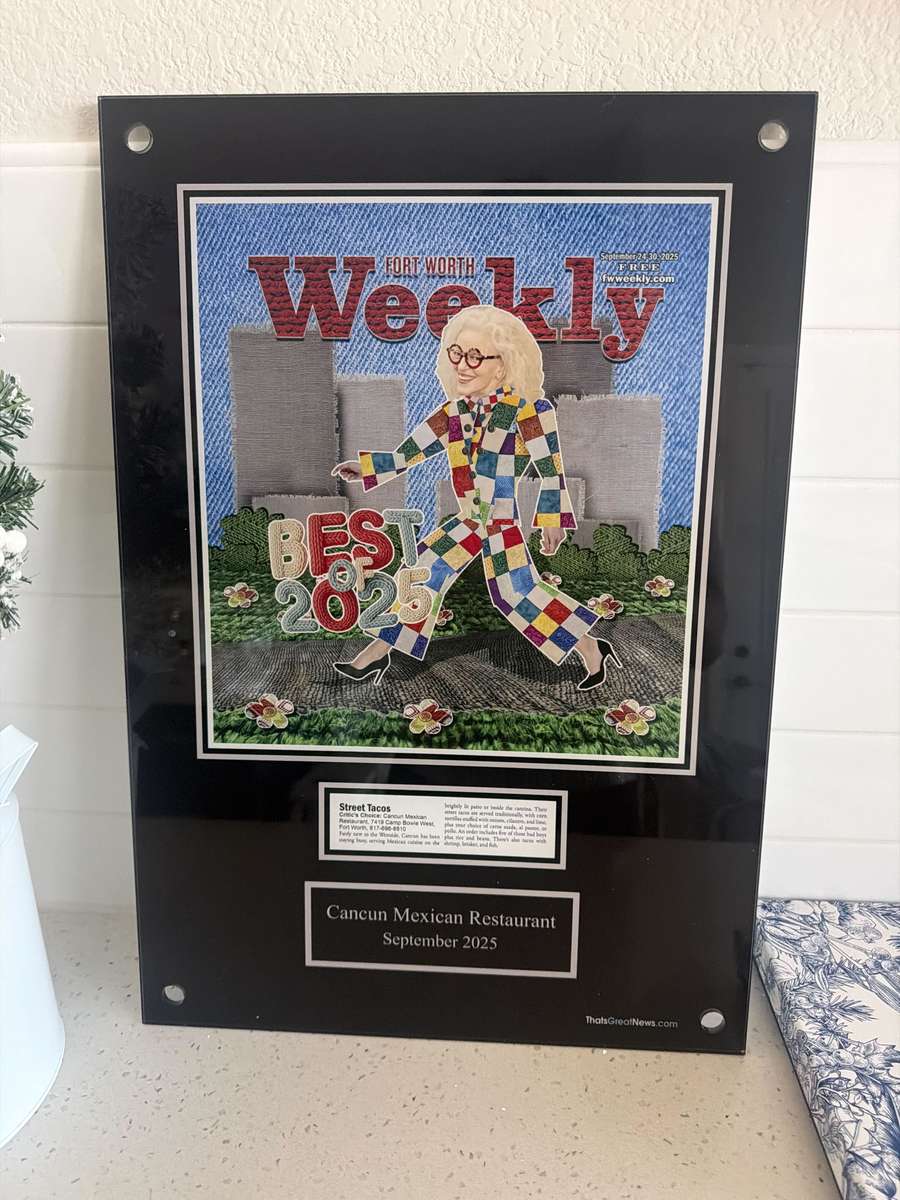 Framed plaque featuring a Fort Worth Weekly "Best of 2025" award given to Cancun Mexican Restaurant. The display includes a colorful magazine cover illustration and a short blurb highlighting the restaurant's street tacos, with a caption noting the award date as September 2025.