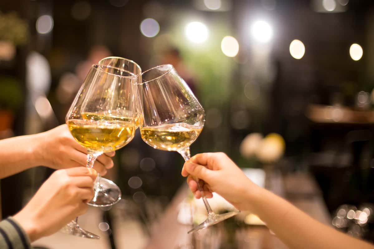 people toasting with glasses of white wine
