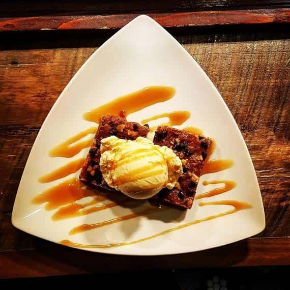 Brownie dessert topped with vanilla ice cream and carmel drizzle