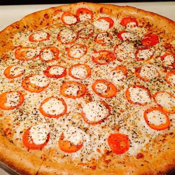 Cheese pizza on a tray with sliced tomatoes and fresh mozzarella