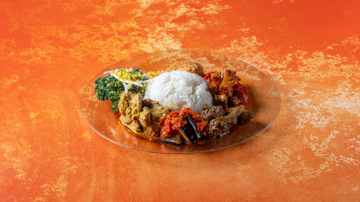 Authentic nasi lemak plate with coconut rice, fried chicken, sambal, anchovies, peanuts, cucumber, and traditional Malaysian sides.