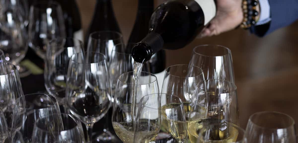 Wine being poured into rows of glasses at a winemaker dinner at 360 Bistro in Belle Meade, Nashville