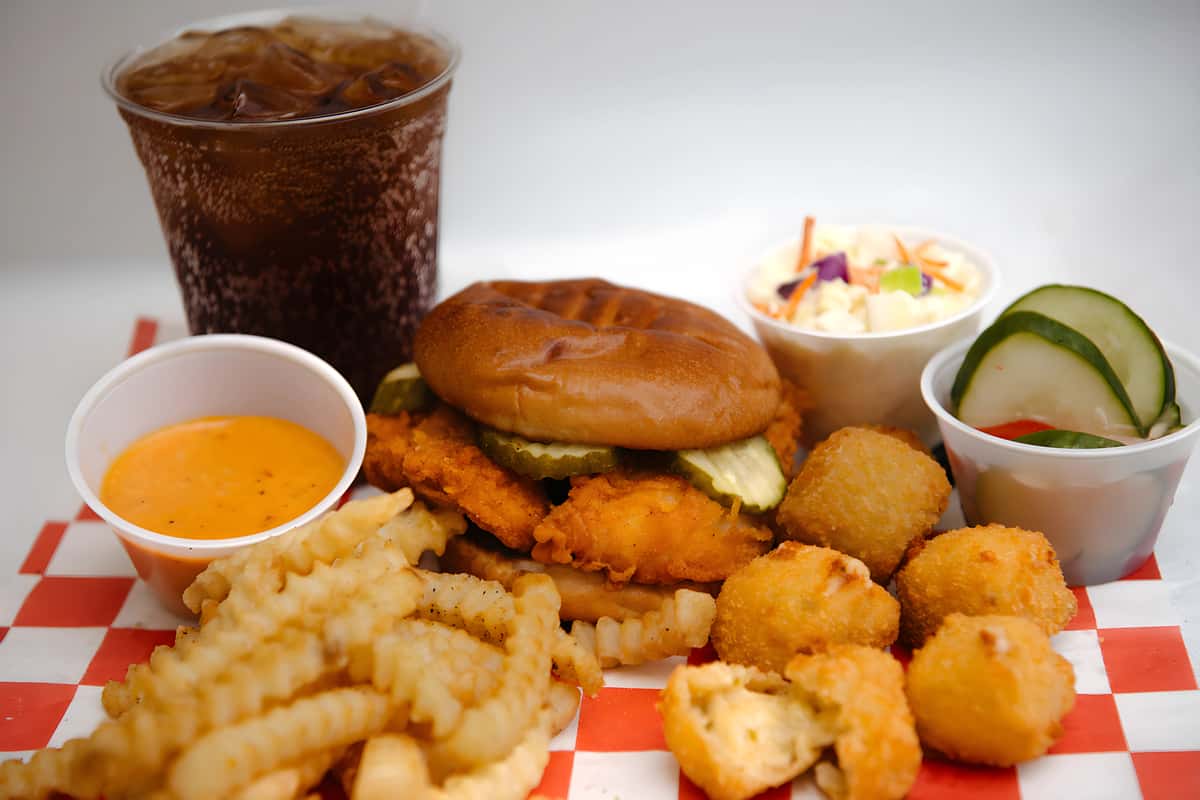 Chicken sandwich combo served with crinkle cut fries, hush puppies, coleslaw, dipping sauce, and a fountain drink.