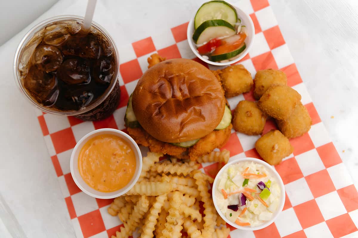 Crispy chicken sandwich platter served with crinkle cut fries, hush puppies, coleslaw, dipping sauce, and a fountain drink.