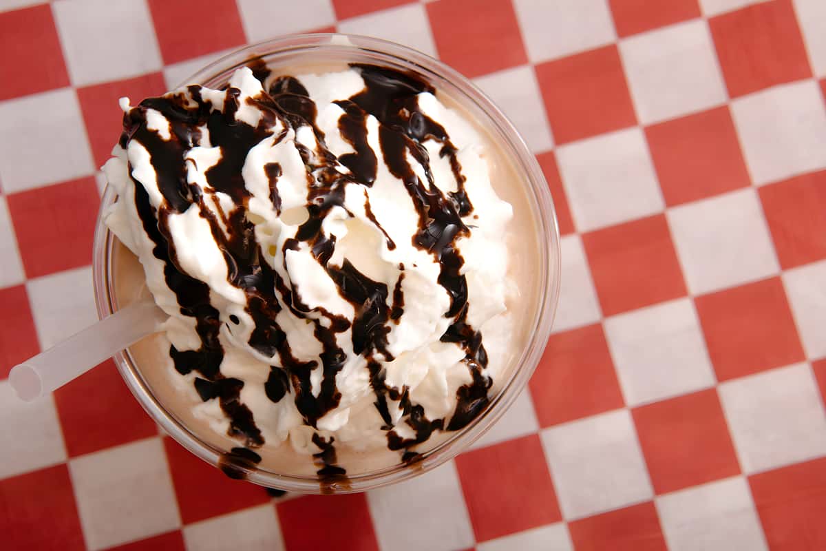 Chocolate milkshake topped with whipped cream and chocolate drizzle.