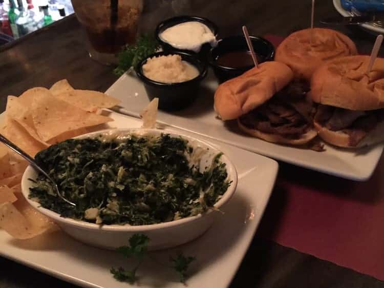 Creamed spinach and tortilla chips in front of three hamburgers