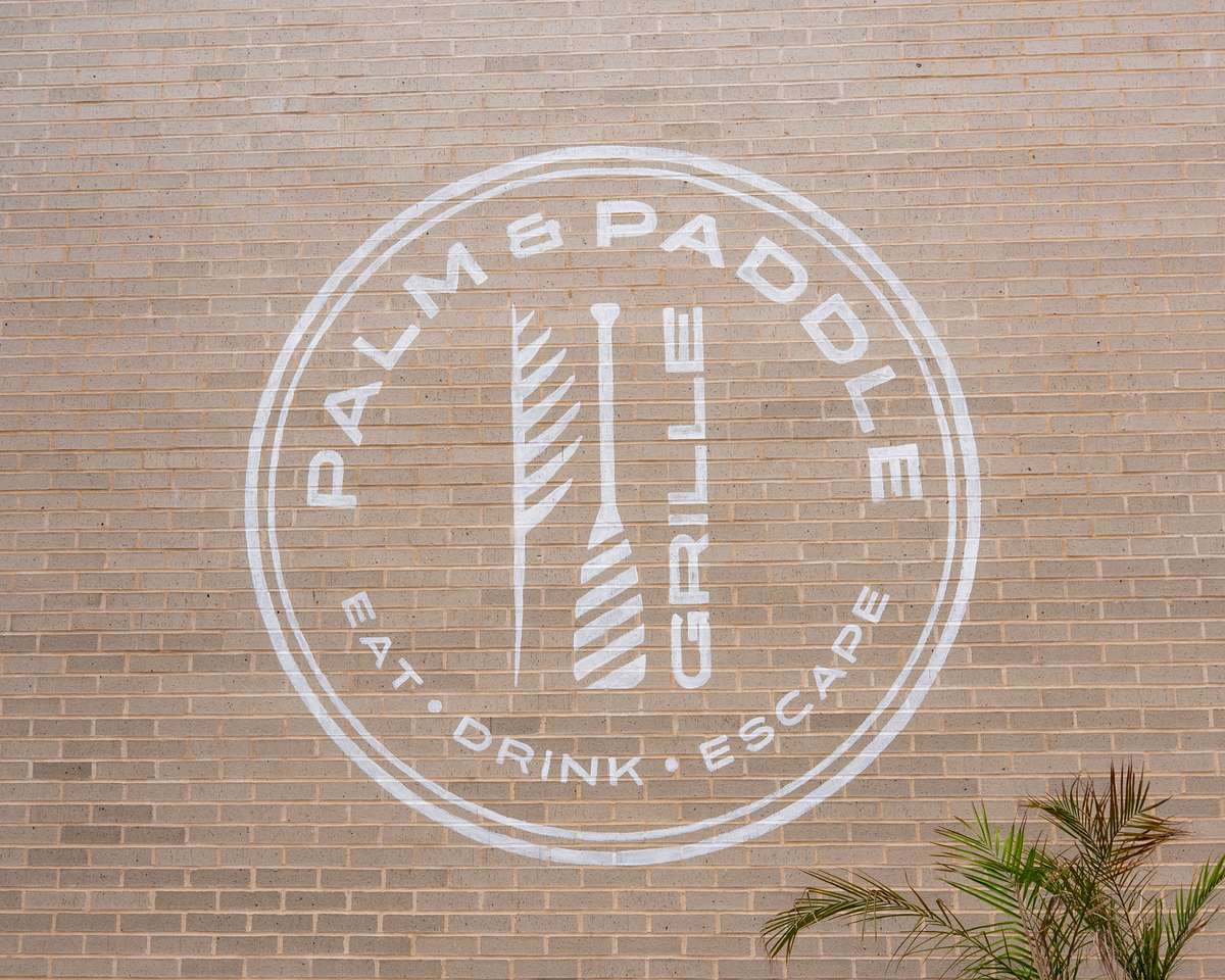 Circular restaurant logo painted on a brick wall.
