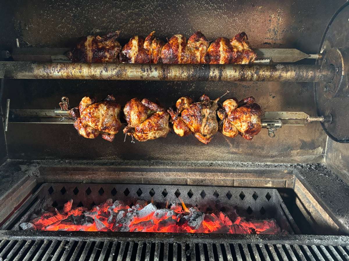 Chicken pieces grilling over open flames inside a barbecue grill.