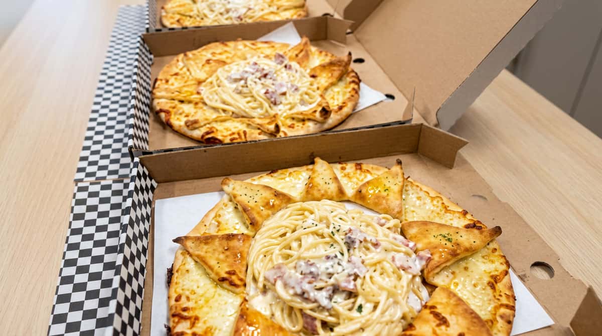 Freshly baked pizzas topped with cheese, onions and herbs in takeaway boxes from Ciao Bella in Westhill