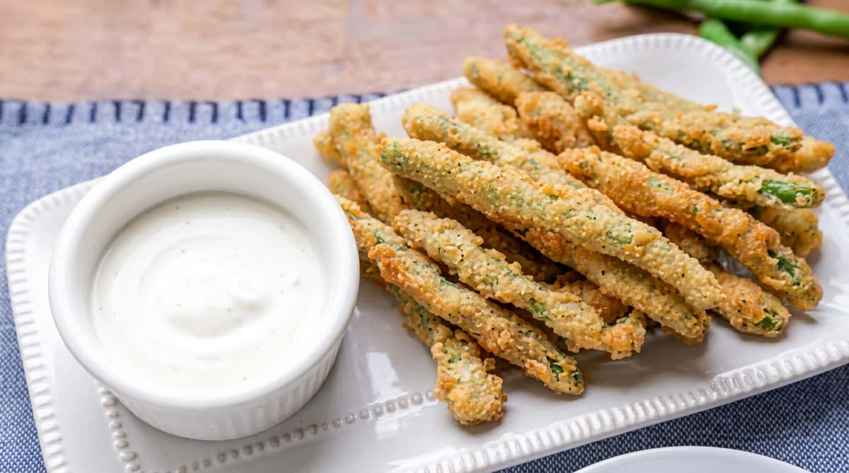 Crispy fried green beans served with a creamy ranch dipping sauce for a crunchy, flavorful appetizer.