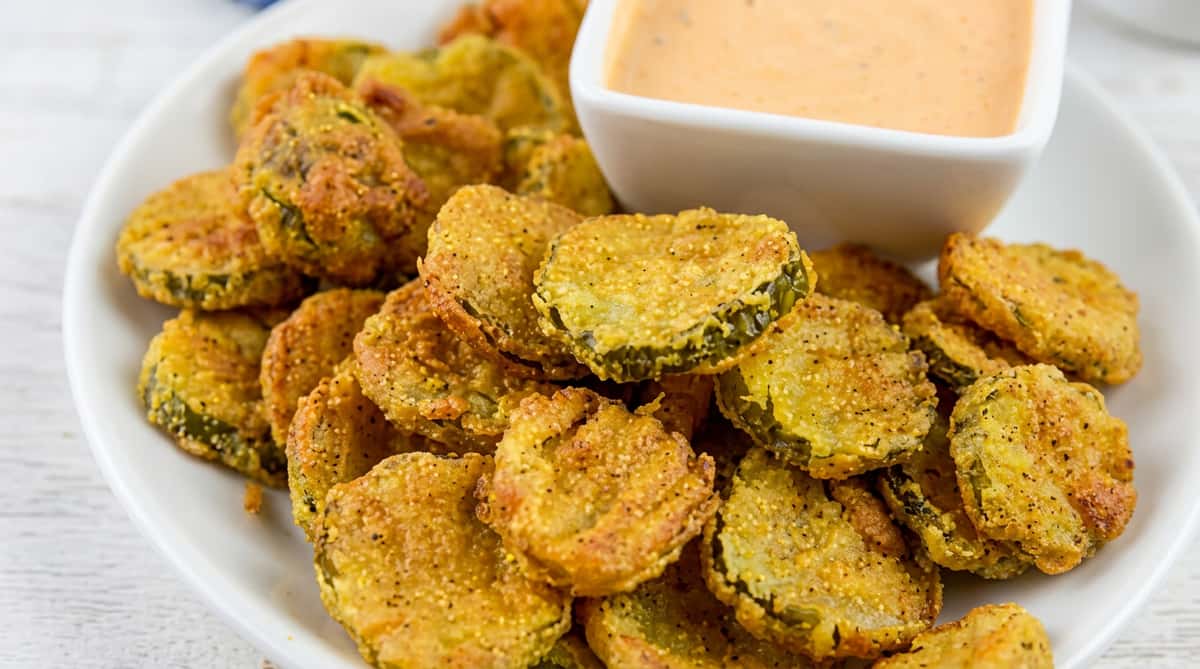 Crispy fried pickle chips served hot with a creamy house dipping sauce for a flavorful appetizer.
