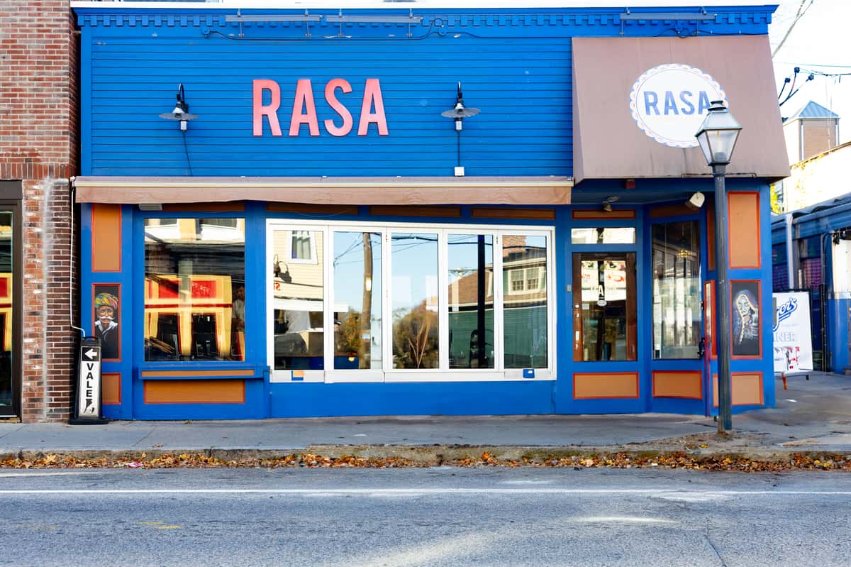 A close-up of the restaurant's exterior, highlighting the entrance with large windows and blue trim, labeled with "Rasa.