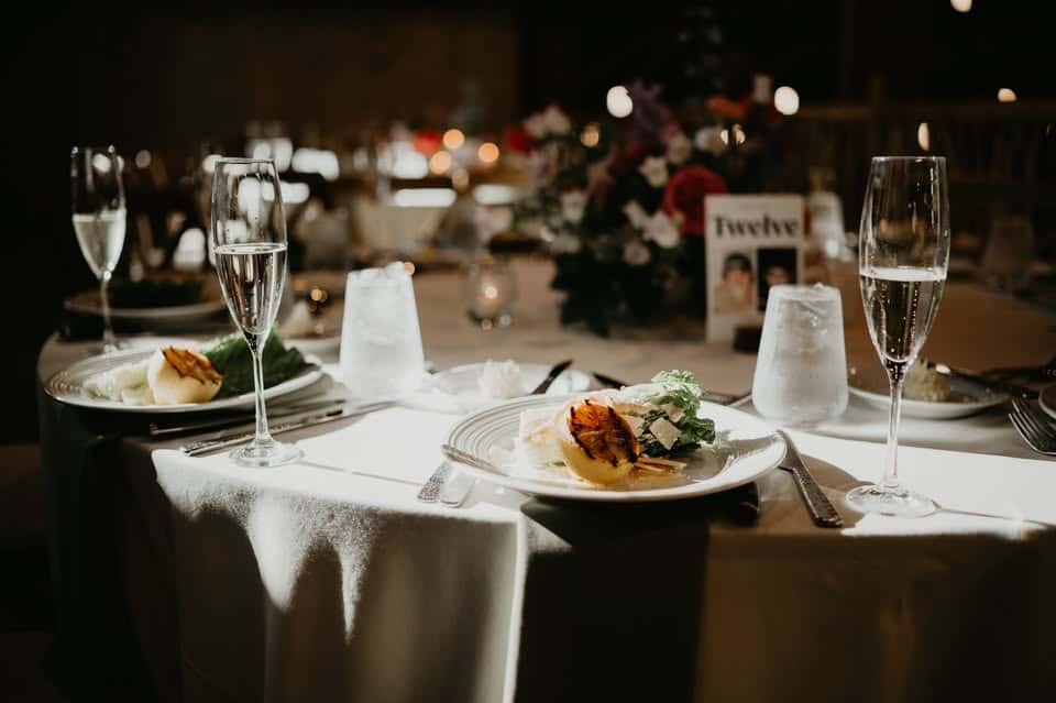White linen table cloth and table with dinner and drink displayed