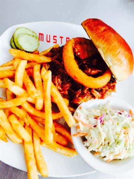 barbecue sandwich with fries, coleslaw and a pickle on the side