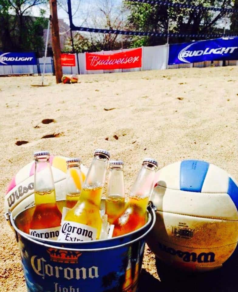 bucket of corona next to a volleyball on a sand court