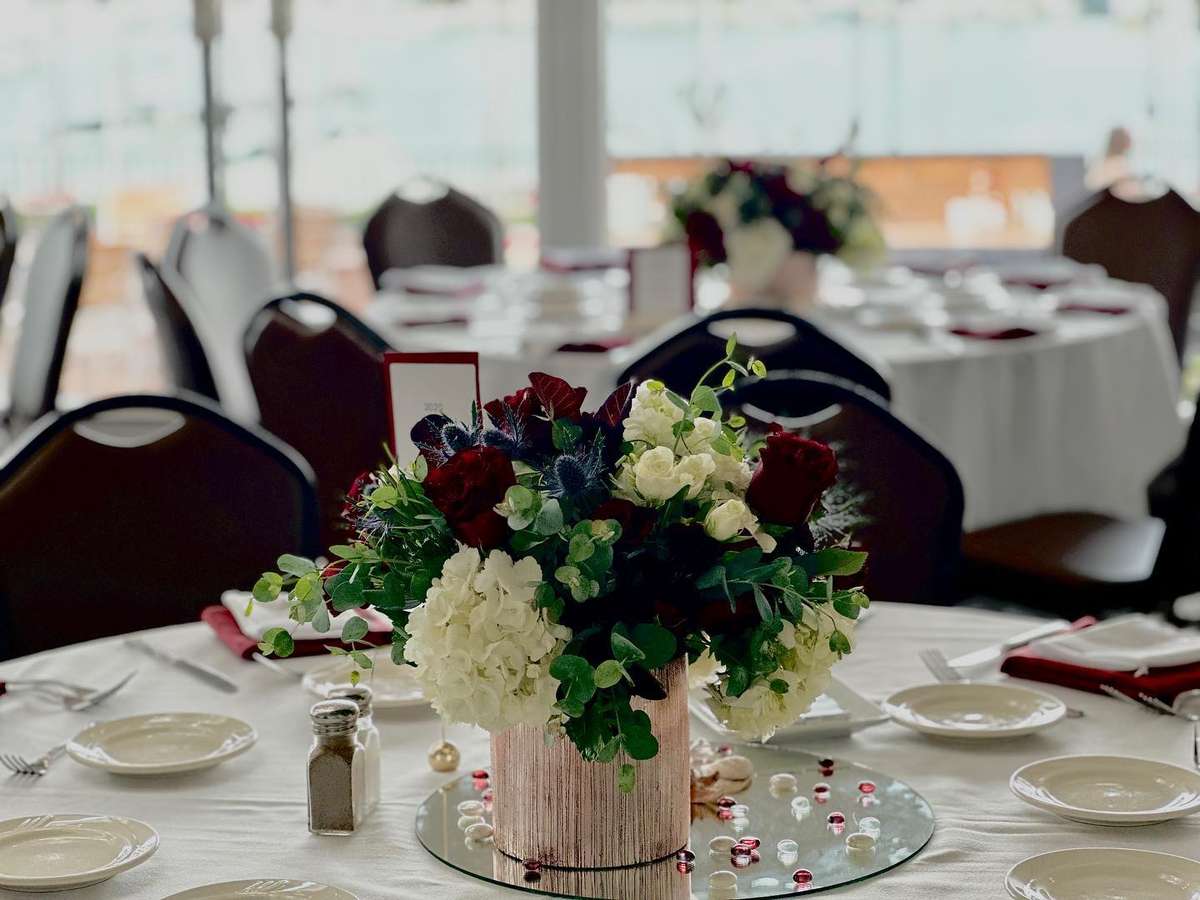 Elegant banquet table centerpiece with white hydrangeas and red roses in a waterfront private dining room