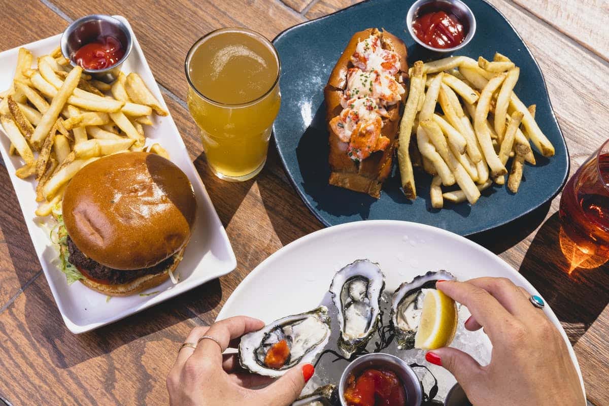 Hand holding oyster and lemon over plates of food