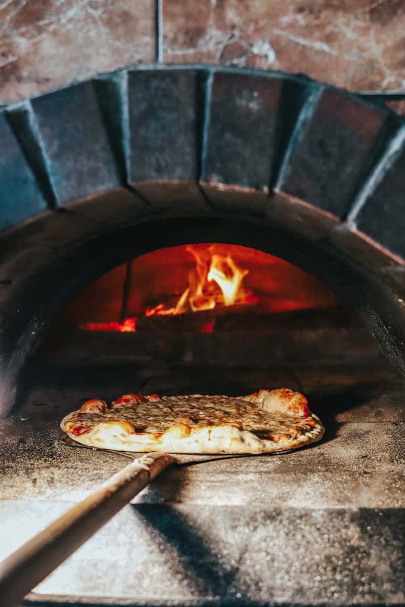 pizza going into brick oven