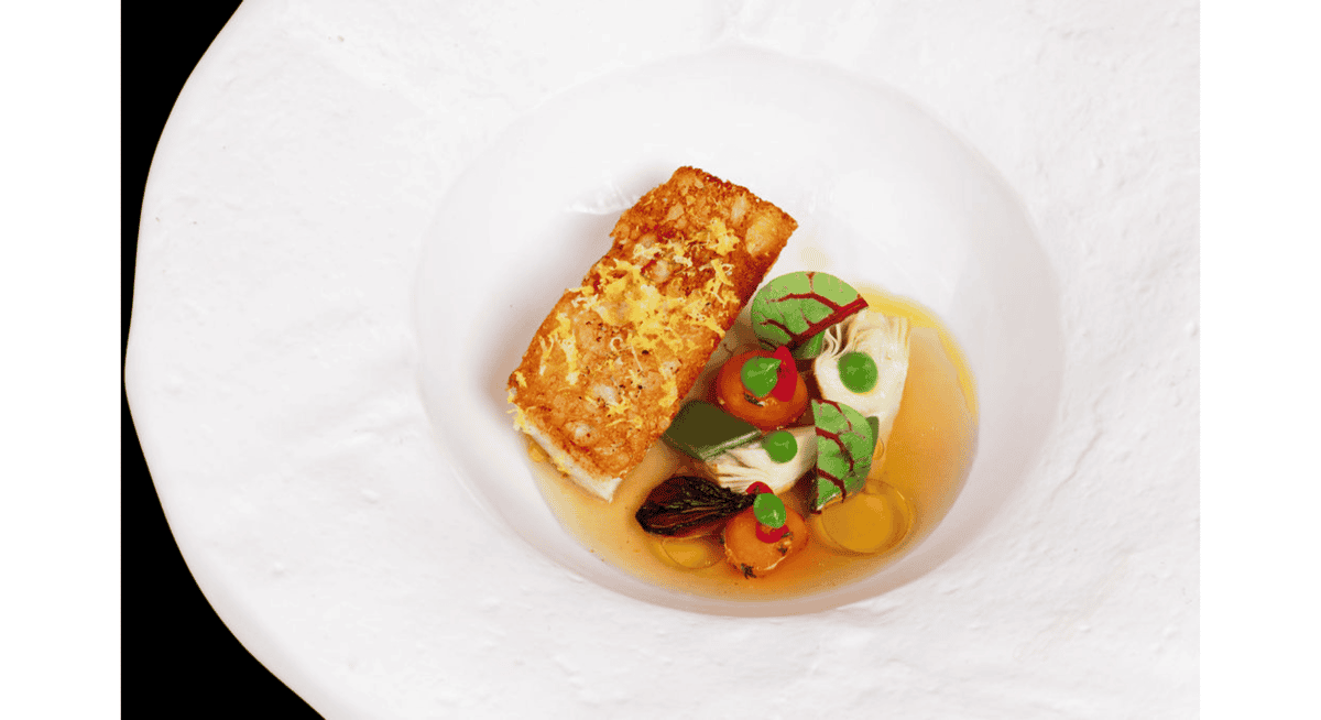 Seared fish with seasonal vegetables, delicate broth, and vibrant garnishes at Stubborn Seed in Miami.