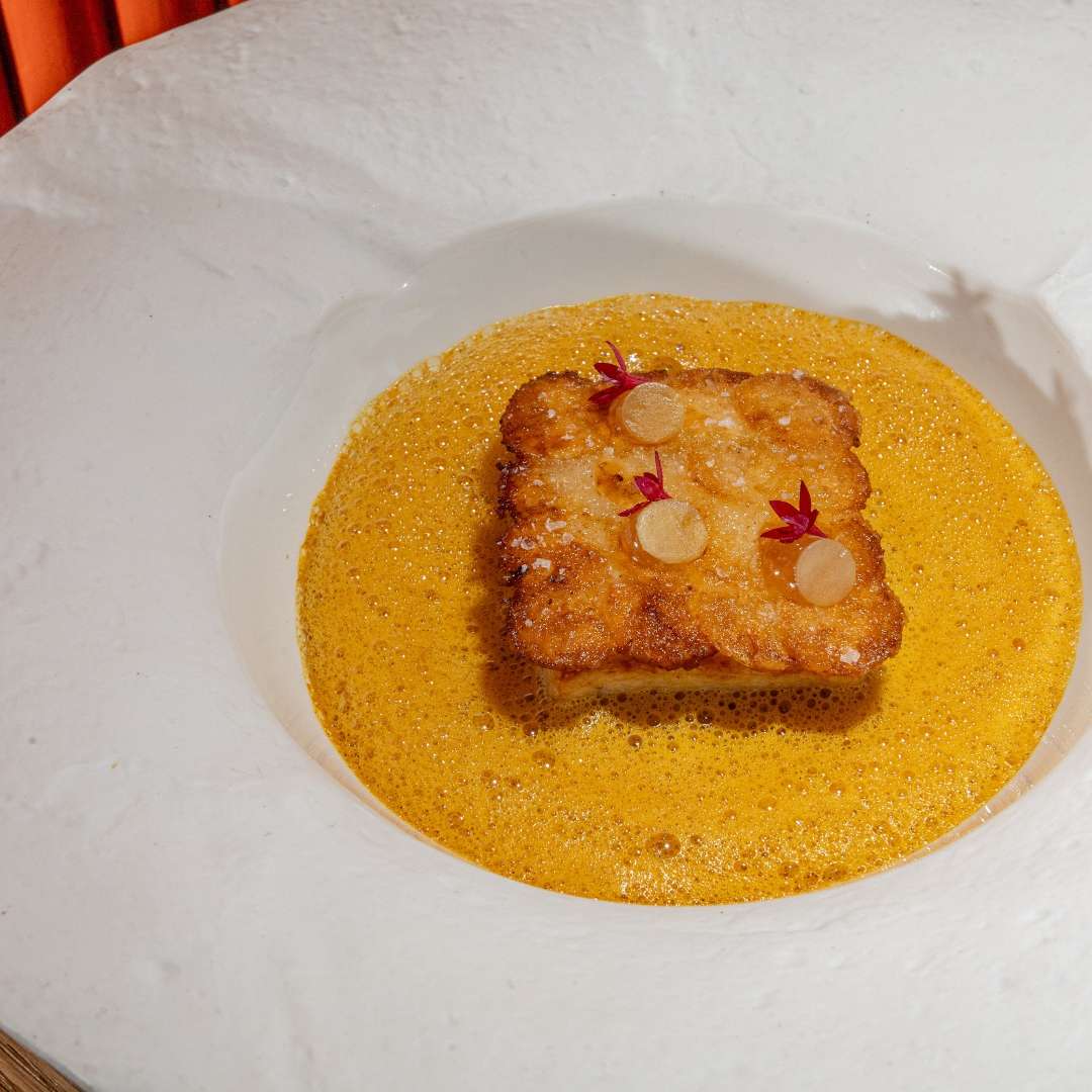Crispy gourmet dish served with orange foam sauce in a white bowl at an upscale Miami restaurant