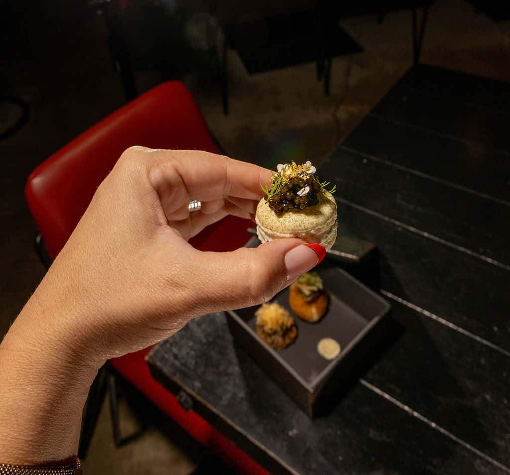 Hand holding an elegant amuse-bouche from a MICHELIN tasting menu experience in Miami fine dining.