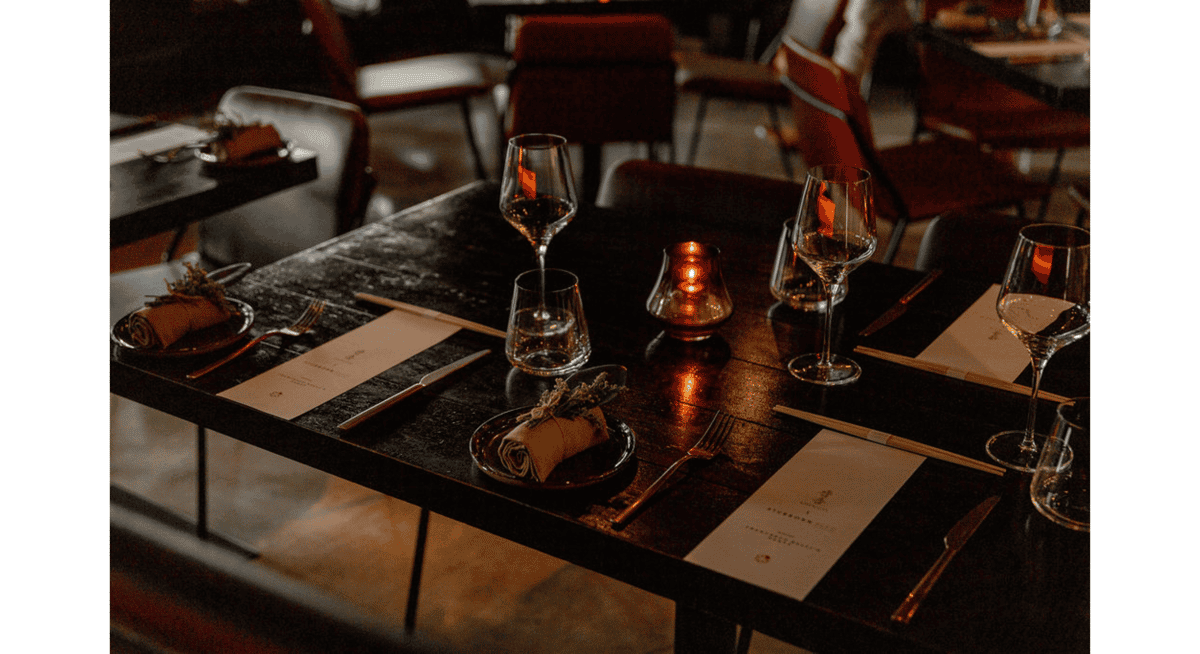 Candlelit fine dining table set with wine glasses, folded napkins, chopsticks, and elegant place settings in a modern restaurant