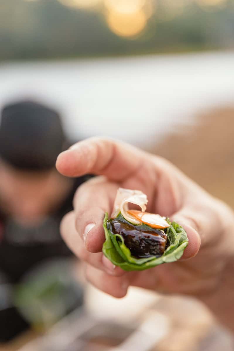 Hand holding a small lettuce wrap bite as part of a creative multi-course dining experience