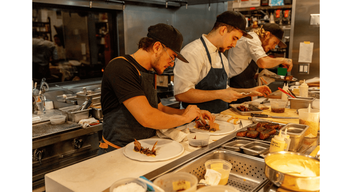Chefs carefully plating gourmet dishes at a professional restaurant kitchen workstation