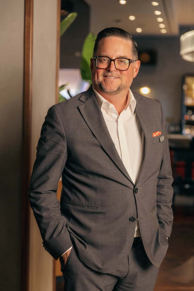 Smiling restaurant professional in a gray suit standing indoors