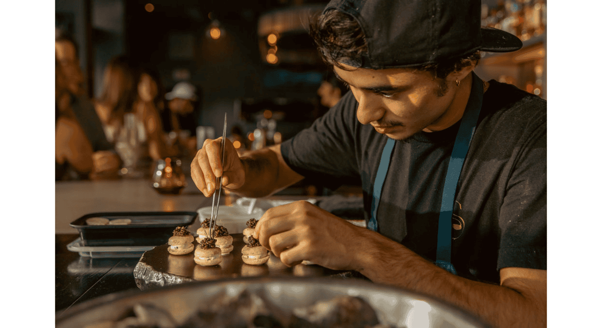 Chef carefully plating bite-sized gourmet appetizers with tweezers in a fine dining restaurant