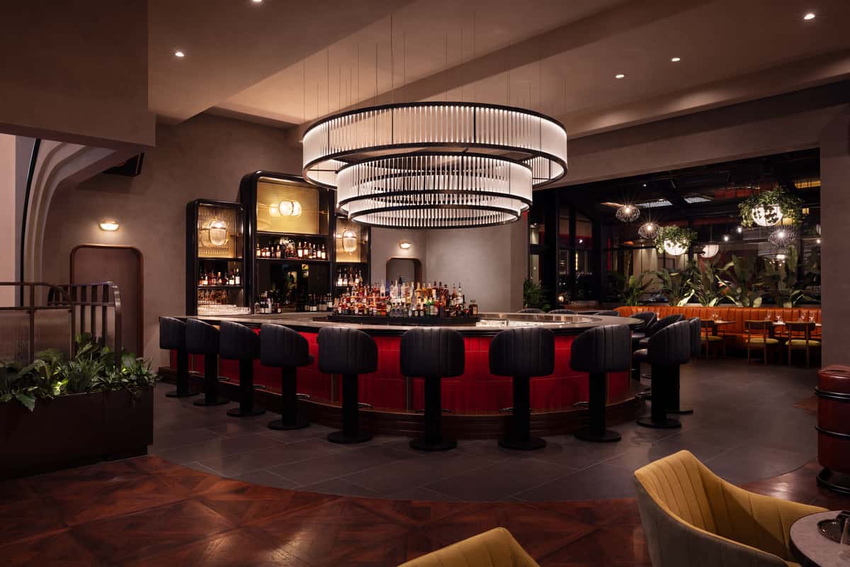 Modern upscale restaurant bar with chandelier lighting, red tile counter, and lounge seating