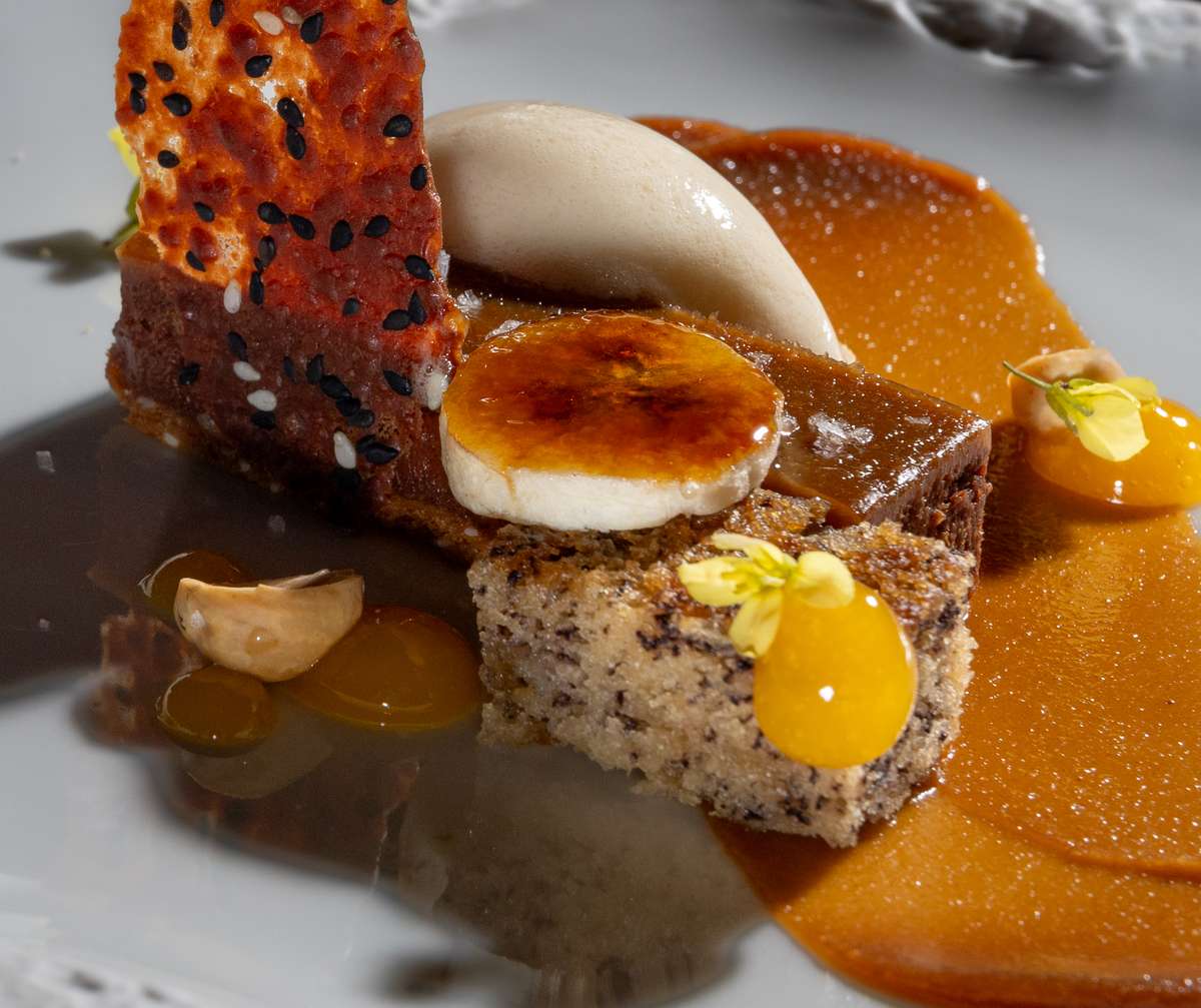 Gourmet plated dessert with caramel, banana, sesame crisp, and ice cream