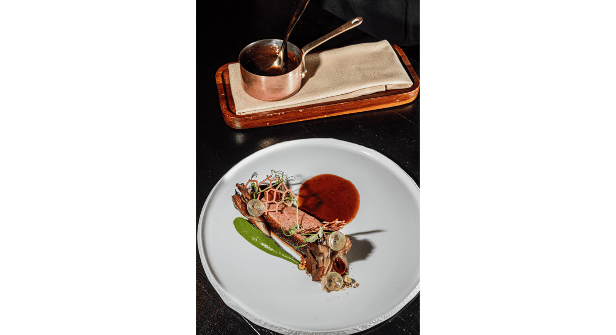 Artfully plated dessert finale with sauce presentation and delicate garnishes in a luxury restaurant setting.