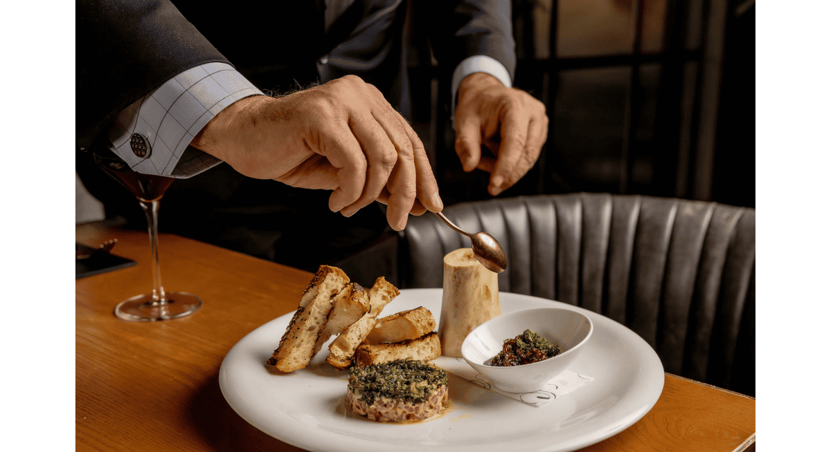Fine dining dish presentation with bone marrow, toasted bread, and tartare served tableside in an upscale Las Vegas restaurant.