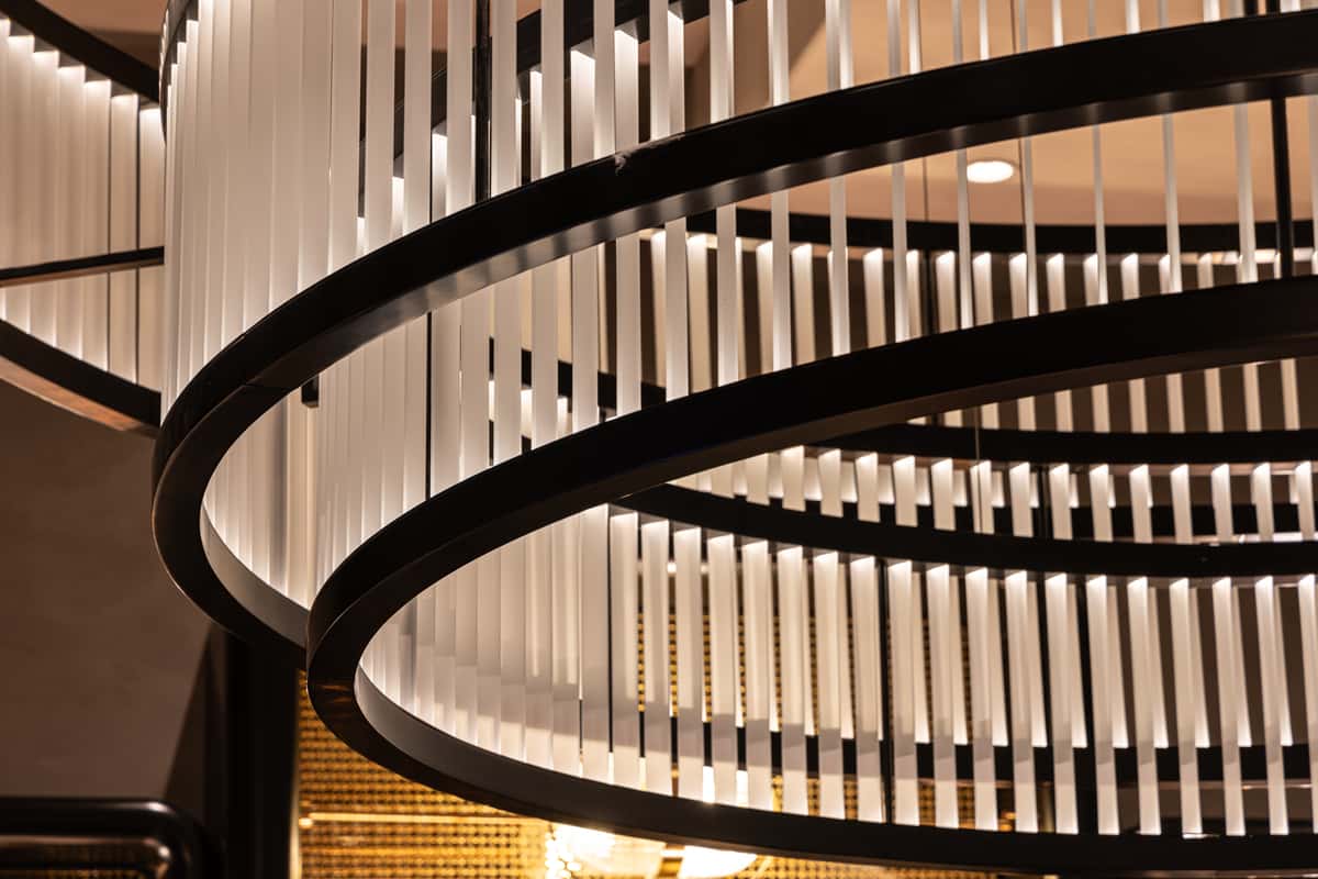 Modern spiral chandelier featuring black circular frames and illuminated vertical panels.